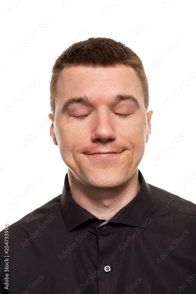 Handsome young man in a black shirt is making faces, while standing isolated on a white background Handsome young man in a black shirt is making faces, while standing isolated on a white background