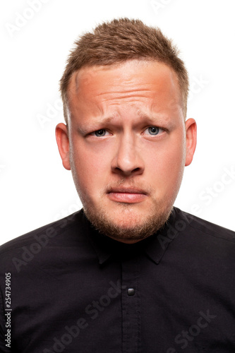 Close up portrait of a confident, blond, handsome young man wearing black shirt, isolated on white background