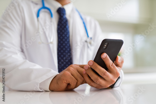Close up middle age doctor man hands using smartphone