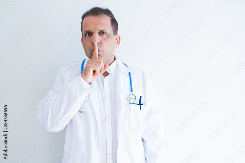 Middle age doctor man wearing stethoscope and medical coat over white background asking to be quiet with finger on lips. Silence and secret concept. Middle age doctor man wearing stethoscope and medical coat over white background asking to be quiet with finger on lips. Silence and secret concept.