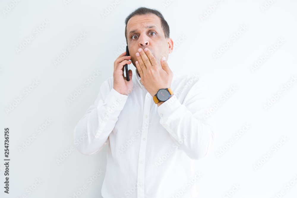 Middle age man calling using smartphone cover mouth with hand shocked with shame for mistake, expression of fear, scared in silence, secret concept Middle age man calling using smartphone cover mouth with hand shocked with shame for mistake, expression of fear, scared in silence, secret concept