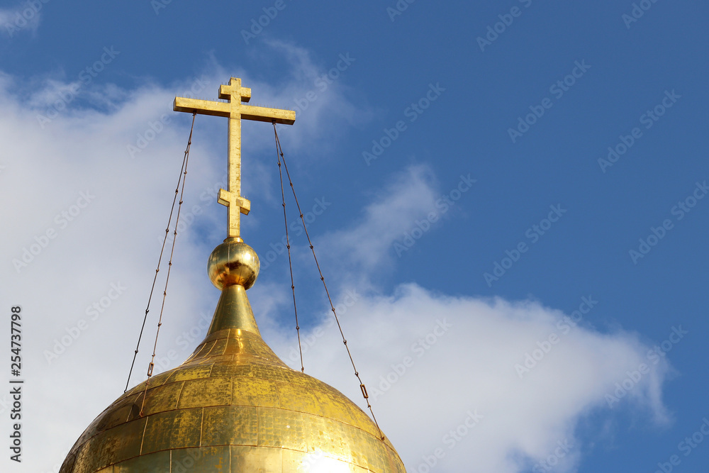 Golden dome of the Orthodox Church with a cross against the blue sky ...
