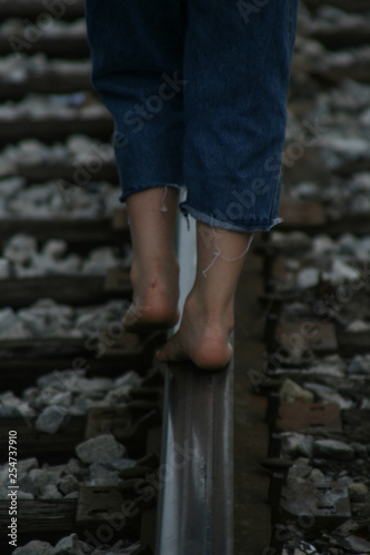 Young boy walks barefoot on abandoned railroad tracks