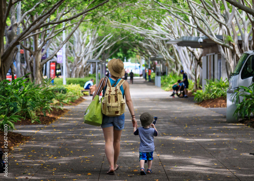 Photo Mother and child walking down tree-lined path in the tropics