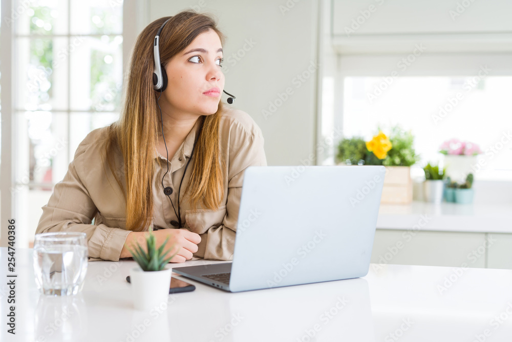Beautiful young operator woman working with laptop and wearing headseat looking to side, relax profile pose with natural face with confident smile. Beautiful young operator woman working with laptop and wearing headseat looking to side, relax profile pose with natural face with confident smile.