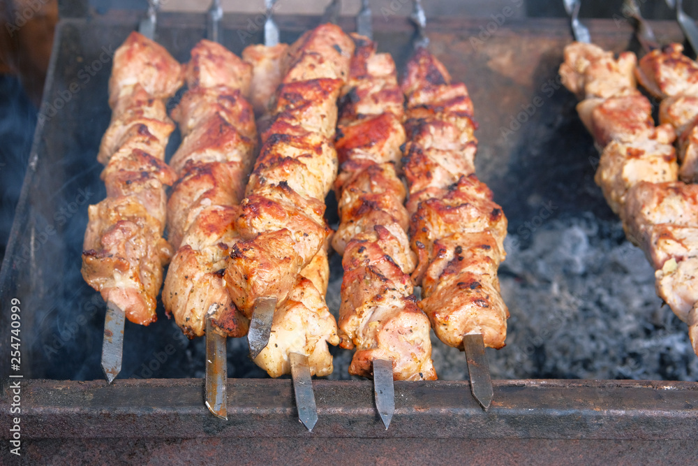 Fried pieces of meat on skewers are roasted on grill at festival outdoor. Shish kebab national cuisine of Central Asia and middle East. Cooking meat on barbecue.