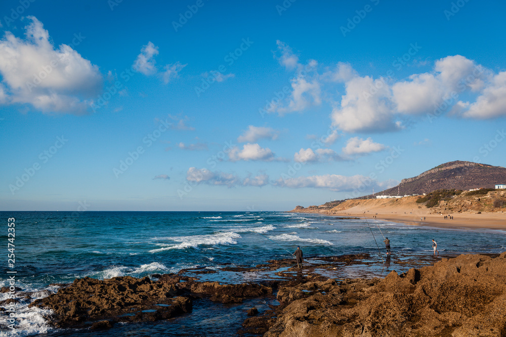 Beach with fishermen and mountain in the background