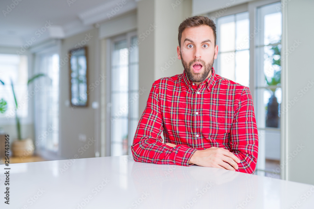 Handsome man wearing colorful shirt afraid and shocked with surprise expression, fear and excited face.