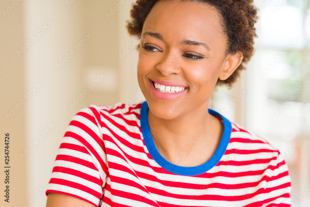 Young beautiful african american woman at home looking away to side with smile on face, natural expression. Laughing confident. Young beautiful african american woman at home looking away to side with smile on face, natural expression. Laughing confident.