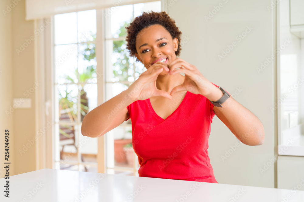 Young beautiful african american woman at home smiling in love showing heart symbol and shape with hands. Romantic concept. Young beautiful african american woman at home smiling in love showing heart symbol and shape with hands. Romantic concept.