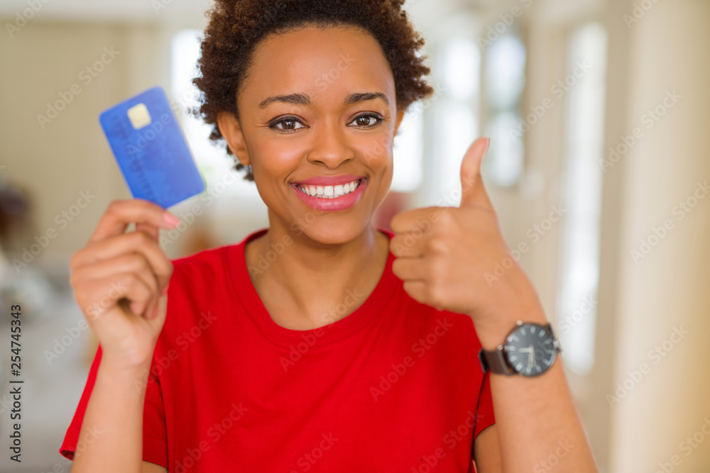 Young african american woman holding credit card happy with big smile doing ok sign, thumb up with fingers, excellent sign Young african american woman holding credit card happy with big smile doing ok sign, thumb up with fingers, excellent sign