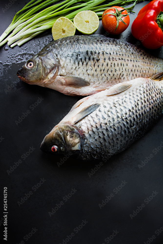 Fresh carp on a dark background with greens and vegetables. Fresh carp on a dark background with greens and vegetables.
