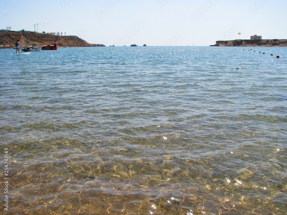 Clear sunny day. Sea transparent water effectively reflects the rays of the sun and blue sky, creating a picturesque   view. 