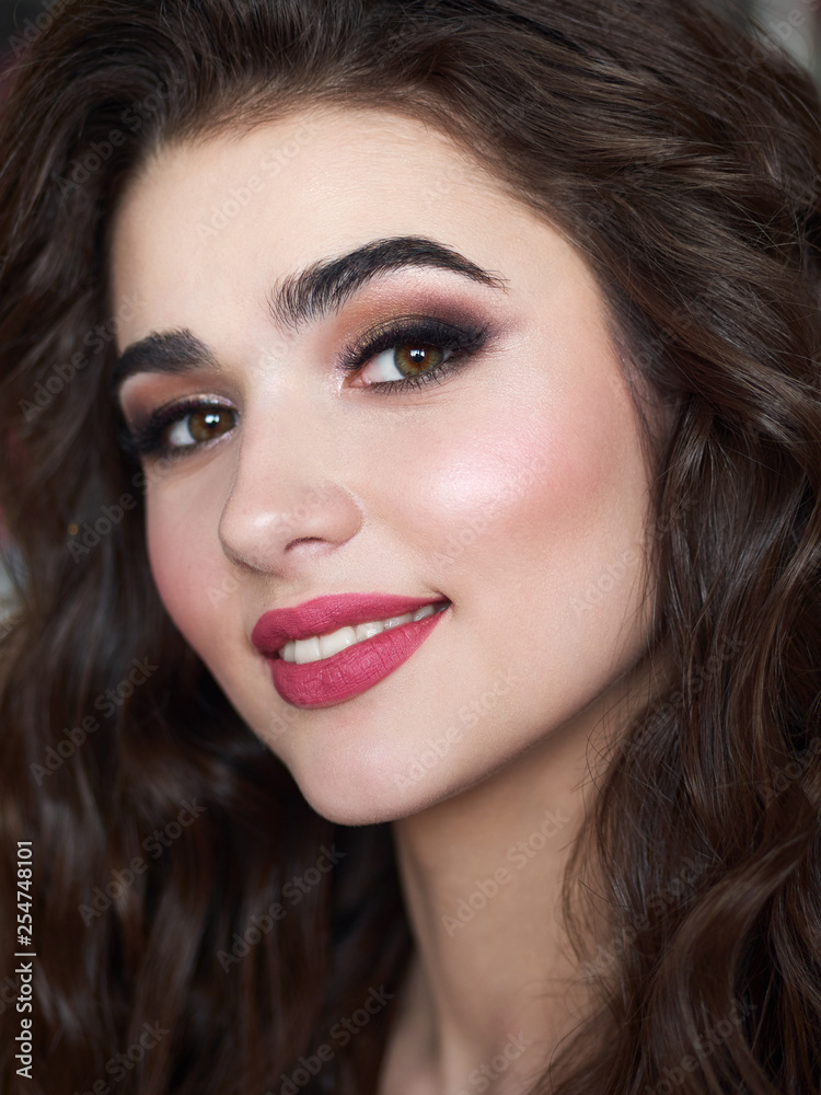 Portrait of beautiful elegant smiling woman with brown curly hair, trendy styling, beautiful makeup, glossy, smooth skin posing for makeup artist social network portfolio Portrait of beautiful elegant smiling woman with brown curly hair, trendy styling, beautiful makeup, glossy, smooth skin posing for makeup artist social network portfolio