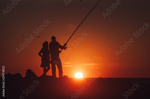 Couple fishing during beautiful and warm sunset