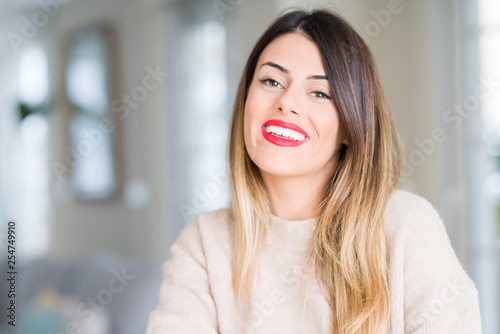 Young beautiful woman wearing winter sweater at home happy face smiling with crossed arms looking at the camera. Positive person. Free Download Young beautiful woman wearing winter sweater at home happy face smiling with crossed arms looking at the camera. Positive person. - GFXLoad