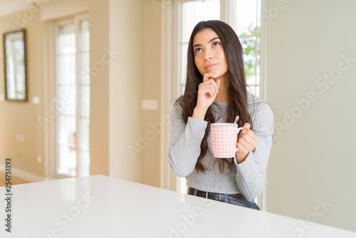 Young woman drinking a cup of coffee serious face thinking about question  very confused idea