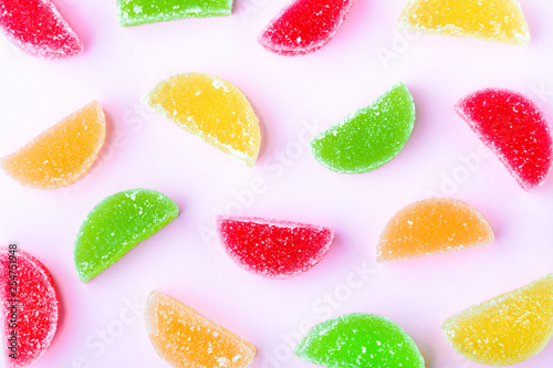 colored fruit jelly with sugar crystals, on a pink background