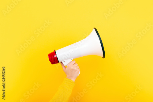 megaphone in hand on a yellow background, attention concept announcement