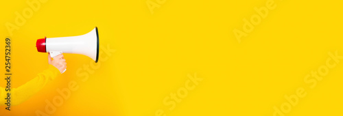 megaphone in hand on a yellow background, panoramic image, attention concept announcement photo