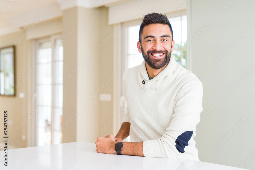 Handsome hispanic man wearing casual white sweater at home with a happy and cool smile on face. Lucky person.