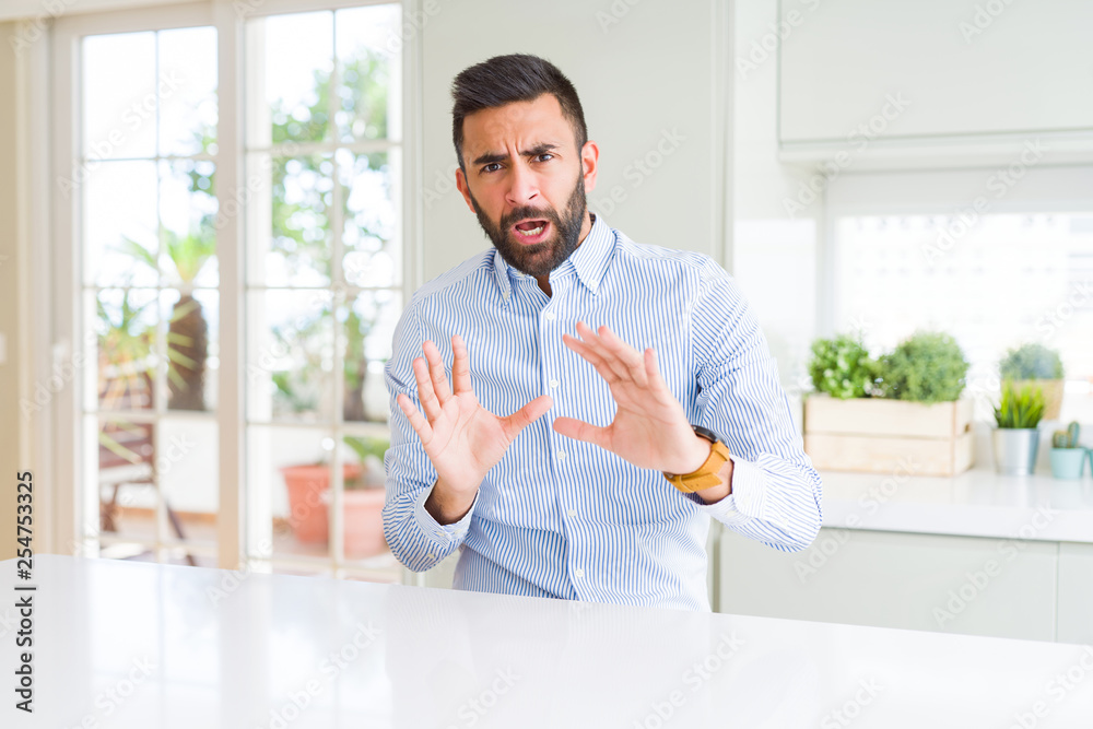 Handsome hispanic business man afraid and terrified with fear expression stop gesture with hands, shouting in shock. Panic concept. Handsome hispanic business man afraid and terrified with fear expression stop gesture with hands, shouting in shock. Panic concept.