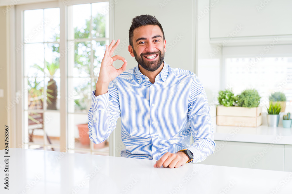 Handsome hispanic business man smiling positive doing ok sign with hand and fingers. Successful expression.