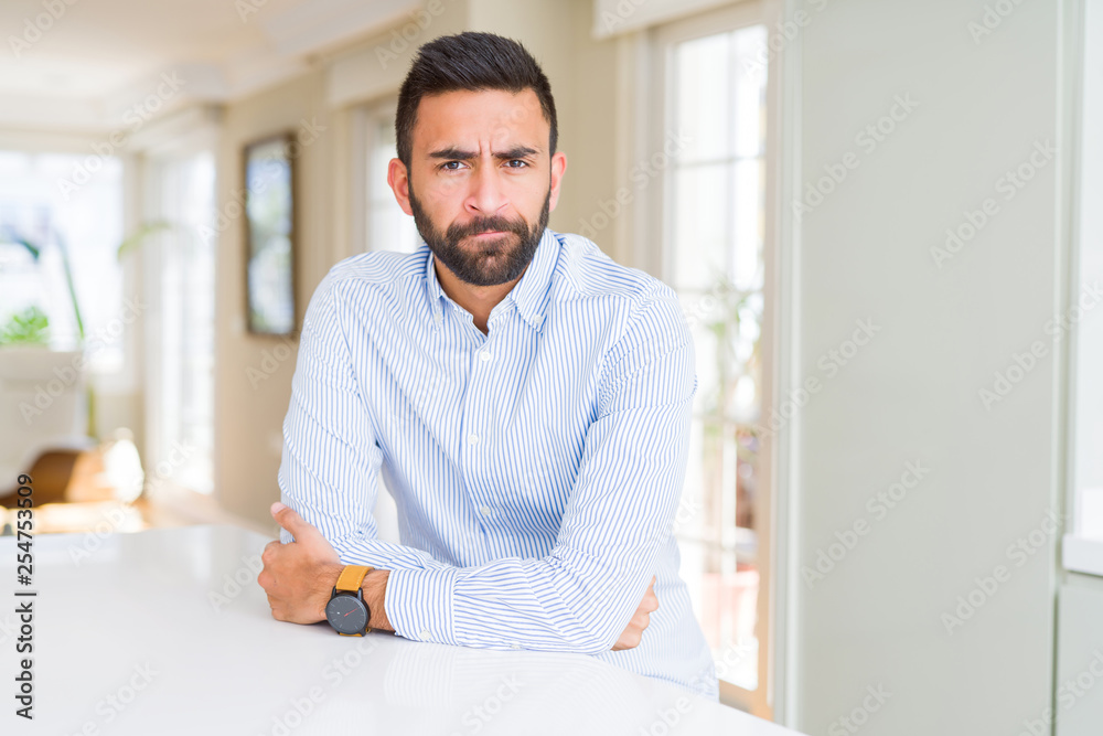 Handsome hispanic business man skeptic and nervous, disapproving expression on face with crossed arms. Negative person.
