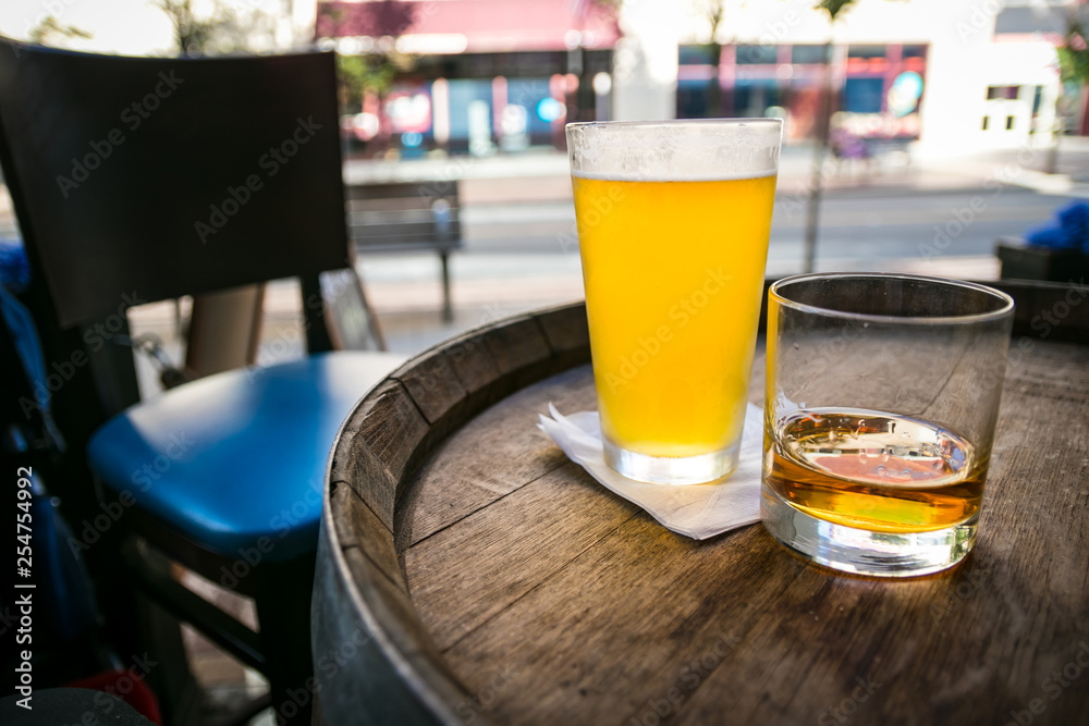 Ice cold pint of beer and whiskey neat in a glass, on an oak barrel table at a city neighborhood restaurant/pub. Ice cold pint of beer and whiskey neat in a glass, on an oak barrel table at a city neighborhood restaurant/pub.