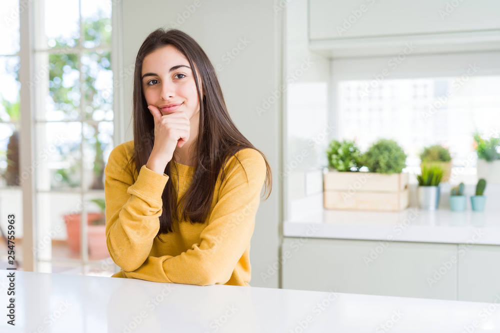Beautiful young woman wearing yellow sweater looking confident at the camera with smile with crossed arms and hand raised on chin. Thinking positive. Beautiful young woman wearing yellow sweater looking confident at the camera with smile with crossed arms and hand raised on chin. Thinking positive.