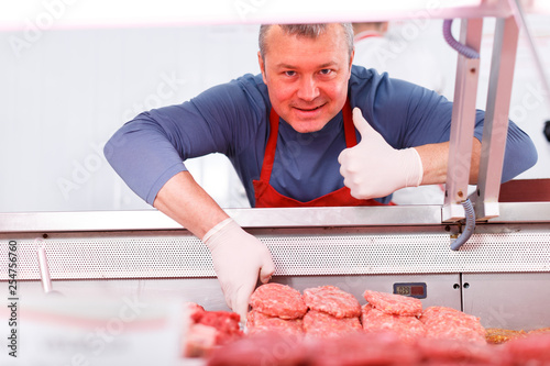 Smiling man putting food into display in shop