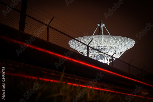 Slika na platnu Satellite dish behind barbed wire with laser security protection.