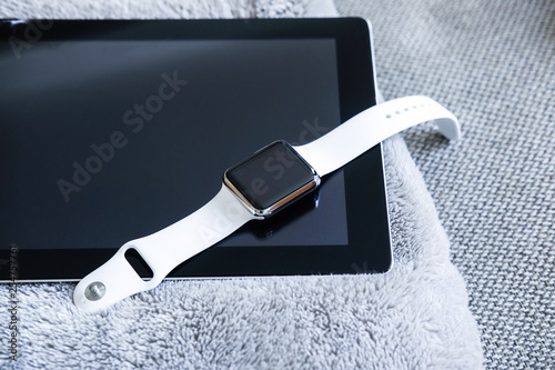 Close-up photo of a smartwatch and tablet lying on terry cloth