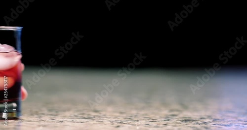 Close up of hand grabbing a mixed cocktail off of bar in slow motion photo