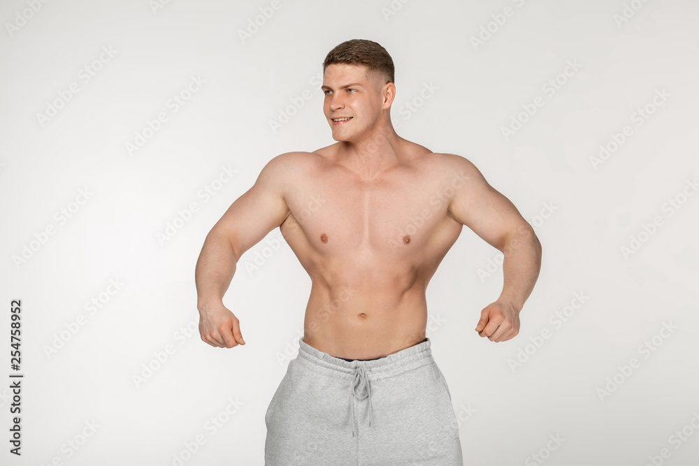 Healthy young man standing strong against grey background