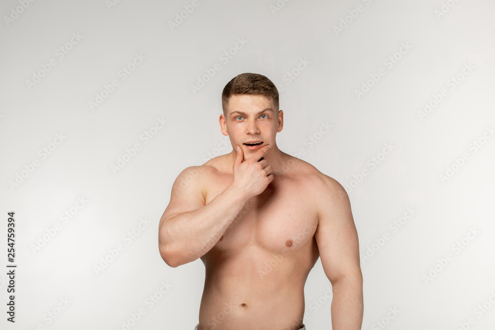 Attractive shirtless sportsman holding his chin and thoughtfully looking at the camera
