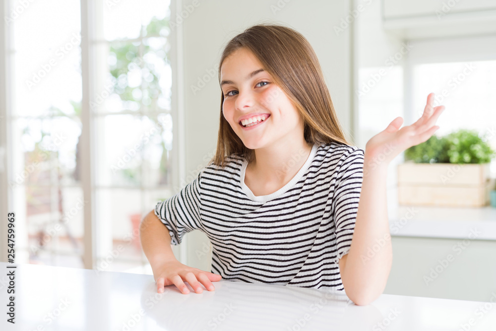 Beautiful young girl kid wearing stripes t-shirt smiling cheerful presenting and pointing with palm of hand looking at the camera. Beautiful young girl kid wearing stripes t-shirt smiling cheerful presenting and pointing with palm of hand looking at the camera.