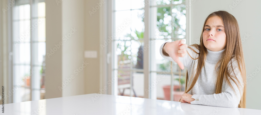 Wide angle picture of beautiful young girl kid wearing casual sweater looking unhappy and angry showing rejection and negative with thumbs down gesture. Bad expression.