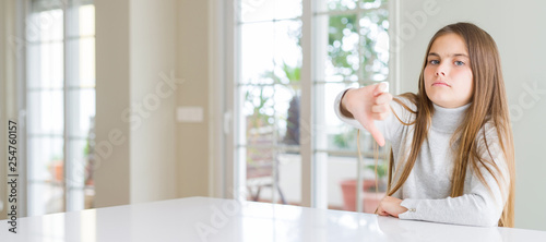 Wide angle picture of beautiful young girl kid wearing casual sweater looking unhappy and angry showing rejection and negative with thumbs down gesture. Bad expression.