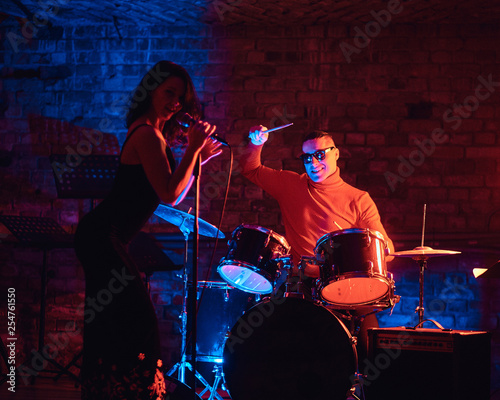 Jazz band performance. Young couple of musicians - a drummer and a singer in a nightclub.