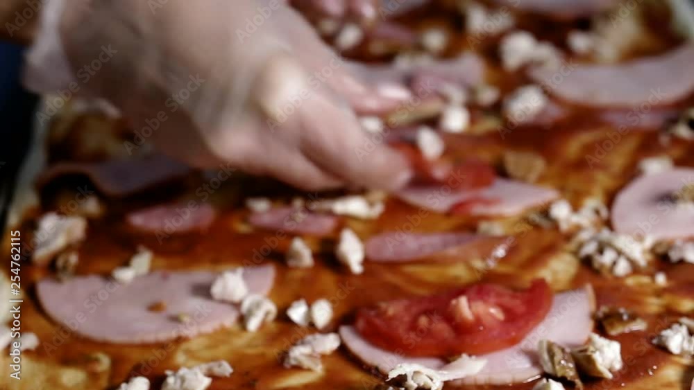 female hands in gloves lay out slices of tomato on pizza female hands in gloves lay out slices of tomato on pizza