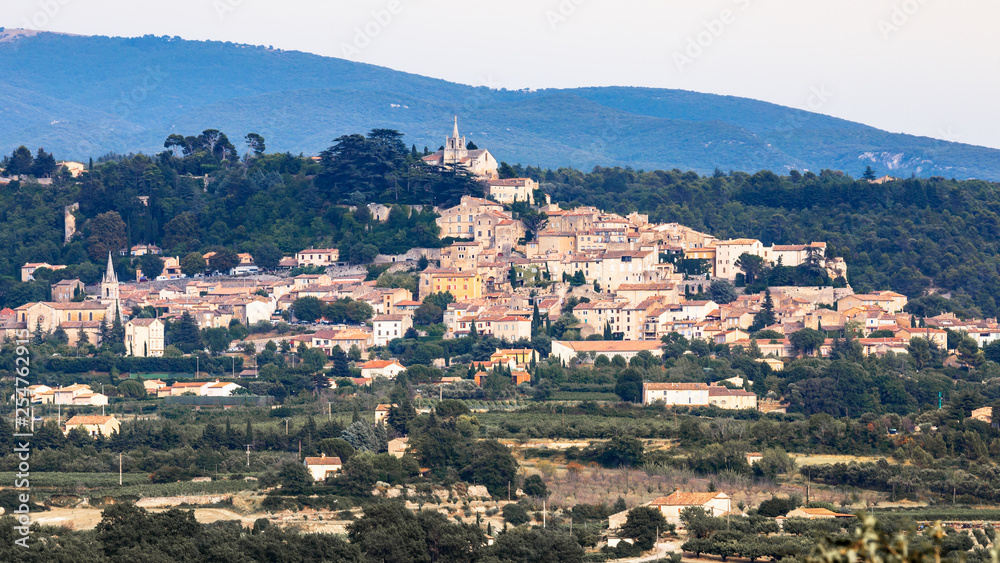 Panoramic view of medieval village Bonnieux in department Vaucluse, fields in the foreground, mountains in the background. Provence, France. Travel France.