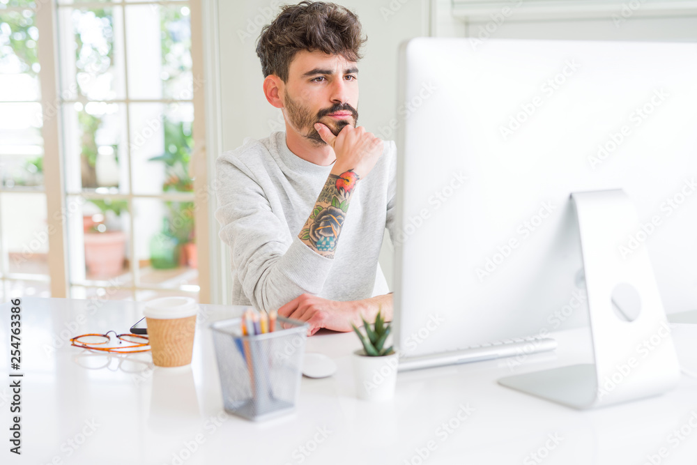 Young man working using computer serious face thinking about question, very confused idea Young man working using computer serious face thinking about question, very confused idea