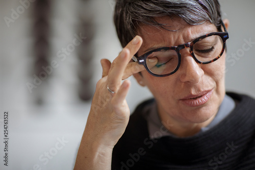 Close-up of stressed businesswoman rubbing eye while sitting in office