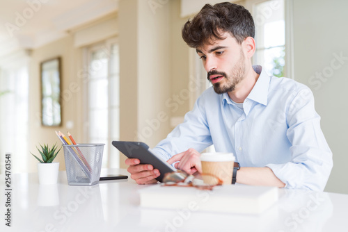 Young business man using touchpad tablet scared in shock with a surprise face, afraid and excited with fear expression