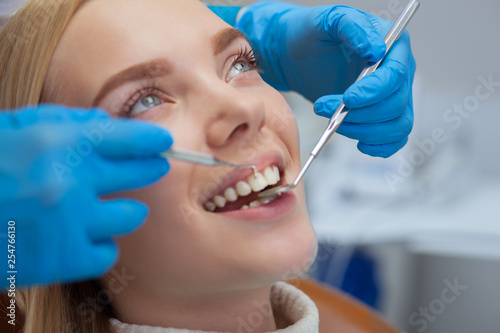 Close up of a beautiful happy woman smiling  while getting her teeth examined by professional dentist. Attractive female patient having dental checkup at dentists office. Smile  whitening concept