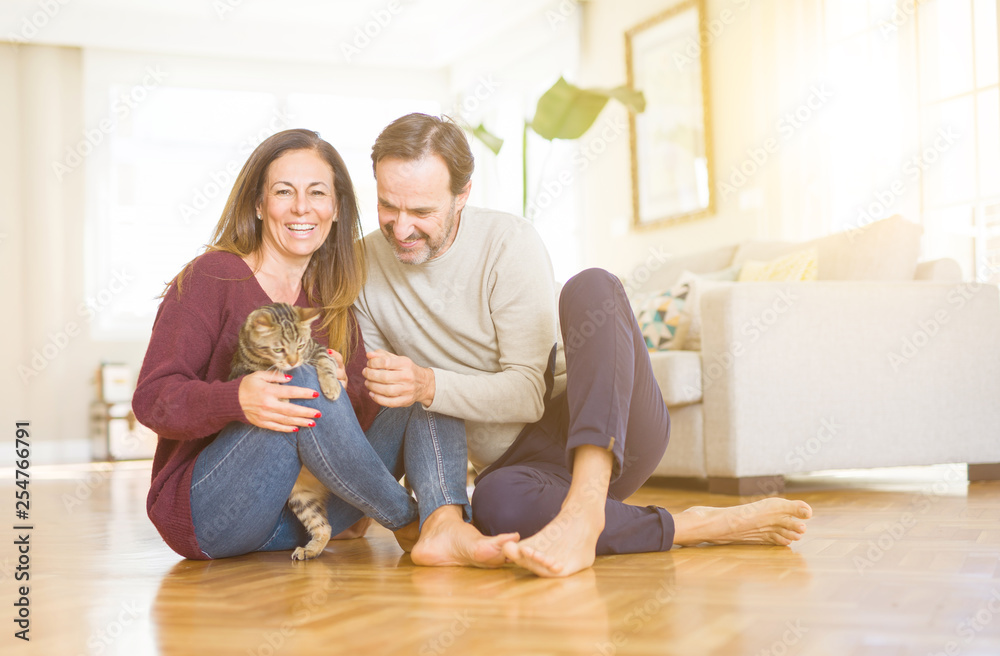Beautiful romantic couple sitting together on the floor with the cat at home Beautiful romantic couple sitting together on the floor with the cat at home