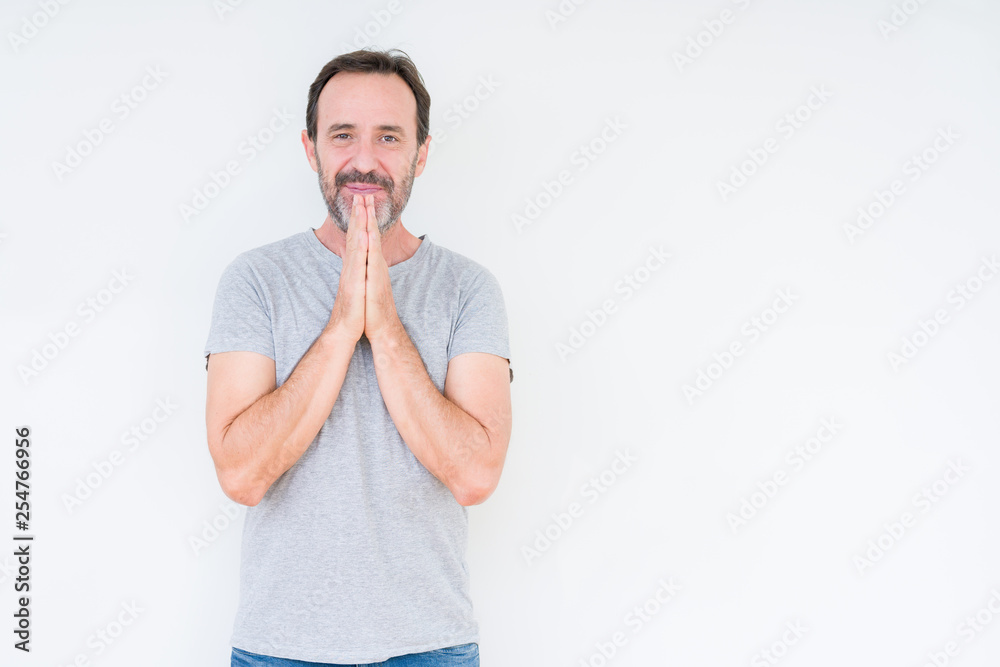 Handsome senior man over isolated background praying with hands together asking for forgiveness smiling confident. Handsome senior man over isolated background praying with hands together asking for forgiveness smiling confident.