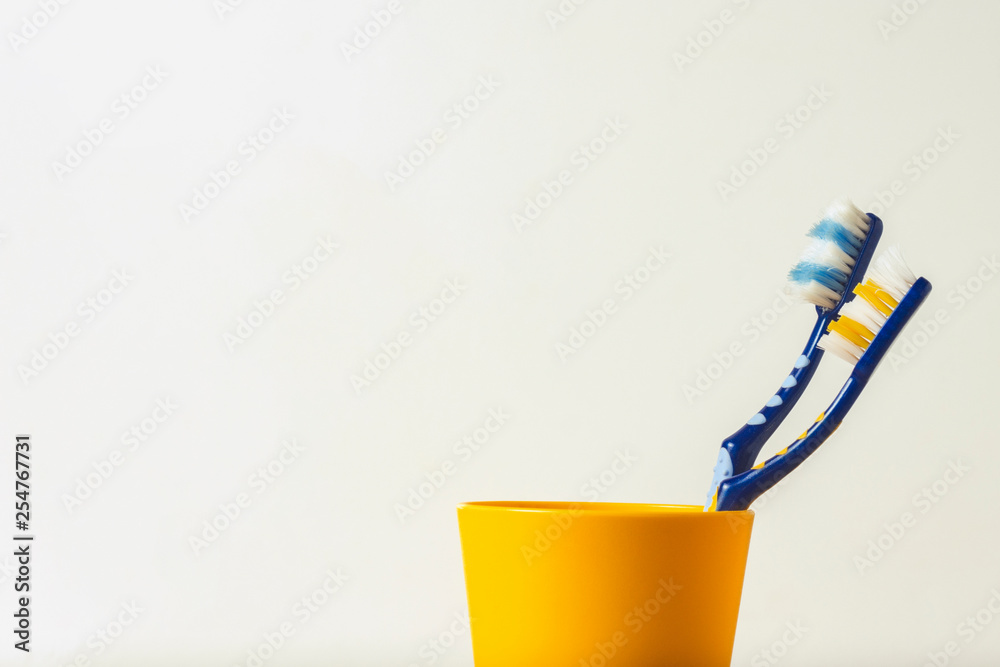 Two used toothbrushes in a plastic cup on a white background. The concept of changing toothbrushes, oral hygiene, dentistry, friendly family. Two used toothbrushes in a plastic cup on a white background. The concept of changing toothbrushes, oral hygiene, dentistry, friendly family.
