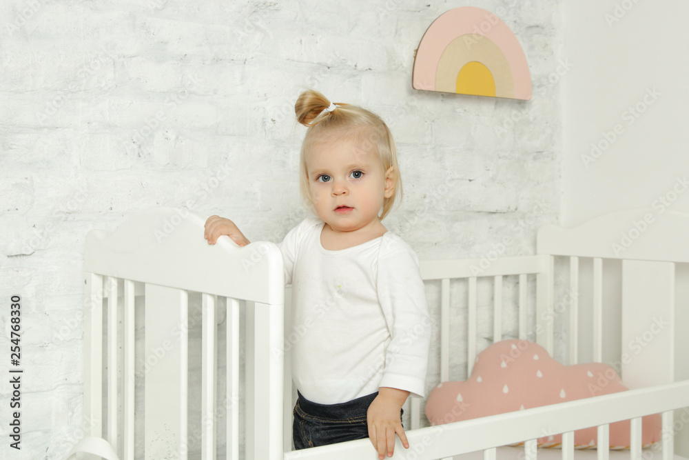 Adorable cheerful baby girl in the crib in the nursery room Adorable cheerful baby girl in the crib in the nursery room